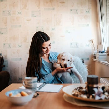 woman with lab puppy feeding it a treat