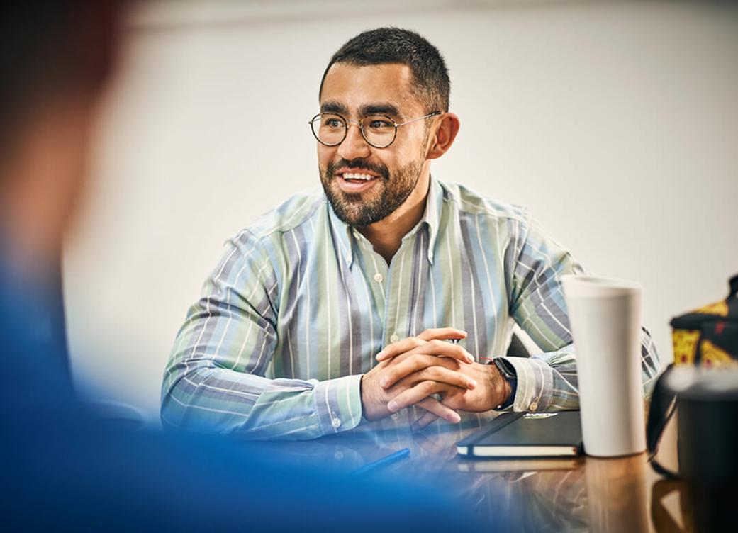 A person smiling at a table in an office