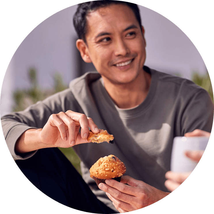 A person smiling and holding a baked good