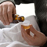 A person pouring medicine into a dosage cup
