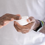 A person holding a jar of cream