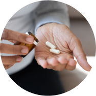 A close-up of hands taking out two white botanical extracts plant based pills from a bottle