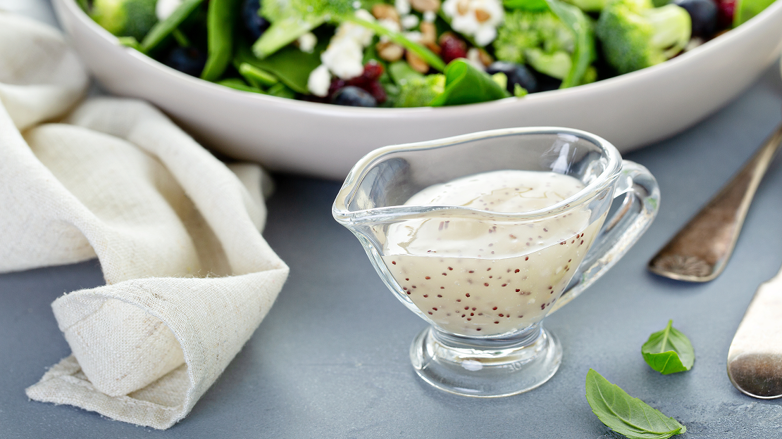 A small glass pouring vessel of white poppyseed dressing 