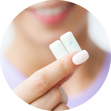 A person holding two pieces of white square chewing gum close to the camera 