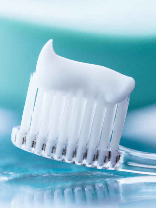 A strip of white toothpaste on the bristles of a clear plastic toothbrush