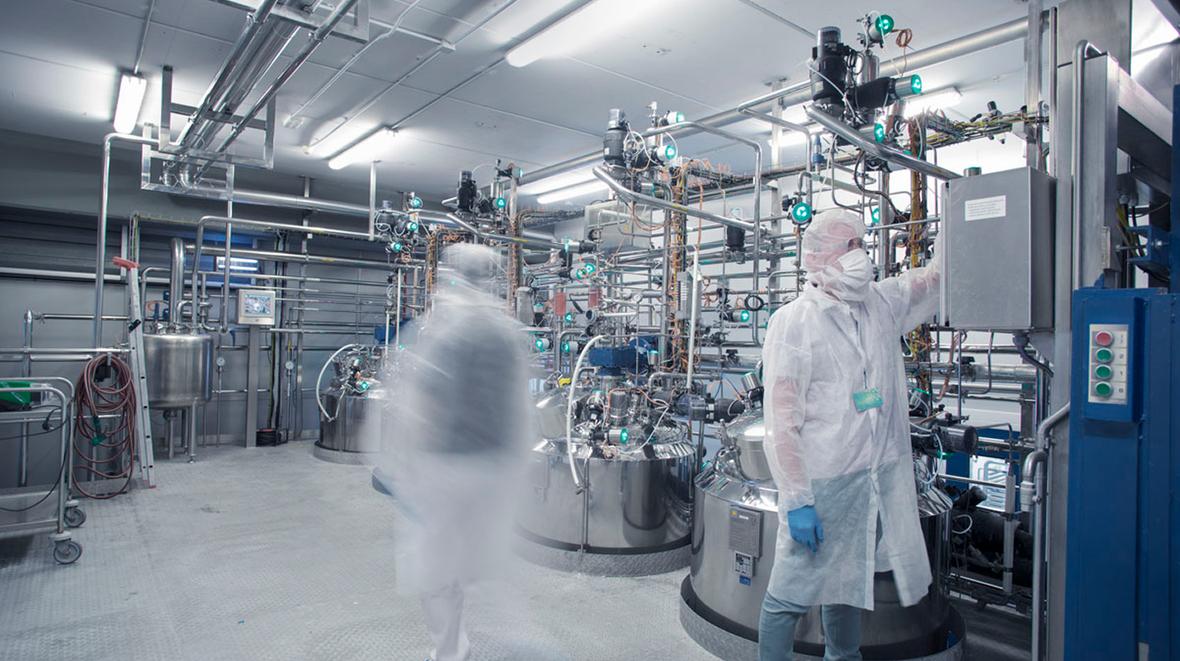 Employees in protective gear operating lab machinery