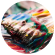 A paintbrush mixing paint on a palette
