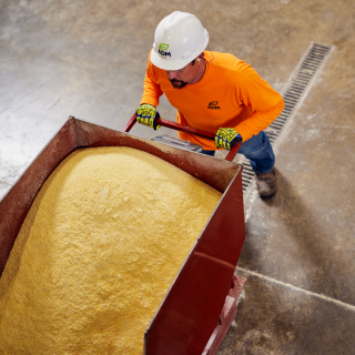 An ADM employee wearing a hardhat standing next to a container of grain