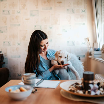woman with lab puppy feeding it a treat