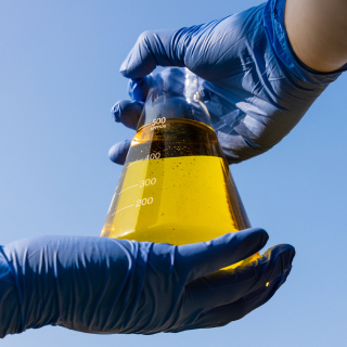 A person’s hands holding a beaker of liquid
