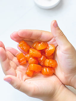 A person’s hands holding orange gummy supplements